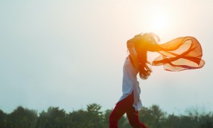 A Woman Running in Front of the Sun Holding a Scarf in the Wind