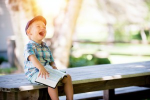 A boy laughing at an open book on his lap