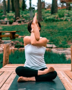 A woman sitting outdoors doing yoga and Om