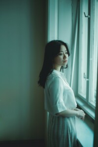 A Woman Solemnly looks out the window