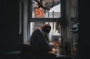 Woman Having Anxiety at Window in Rain