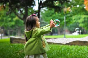 Child popping bubbles in a field